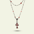 Necklace with a red and black cross pendant on a beige background