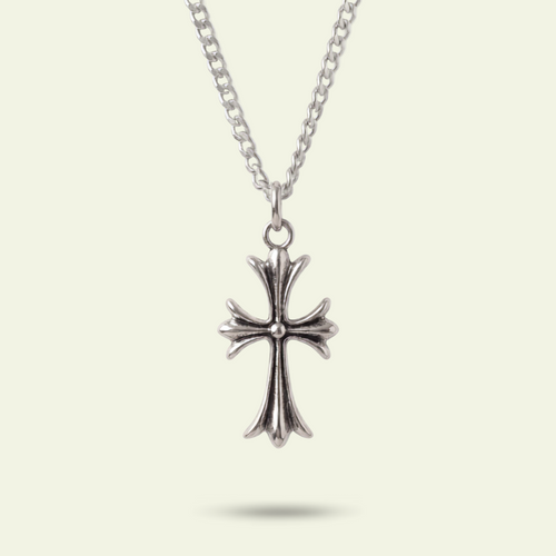 Silver cross pendant necklace on a light beige background
