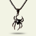 Spider-shaped pendant on a chain against a light background