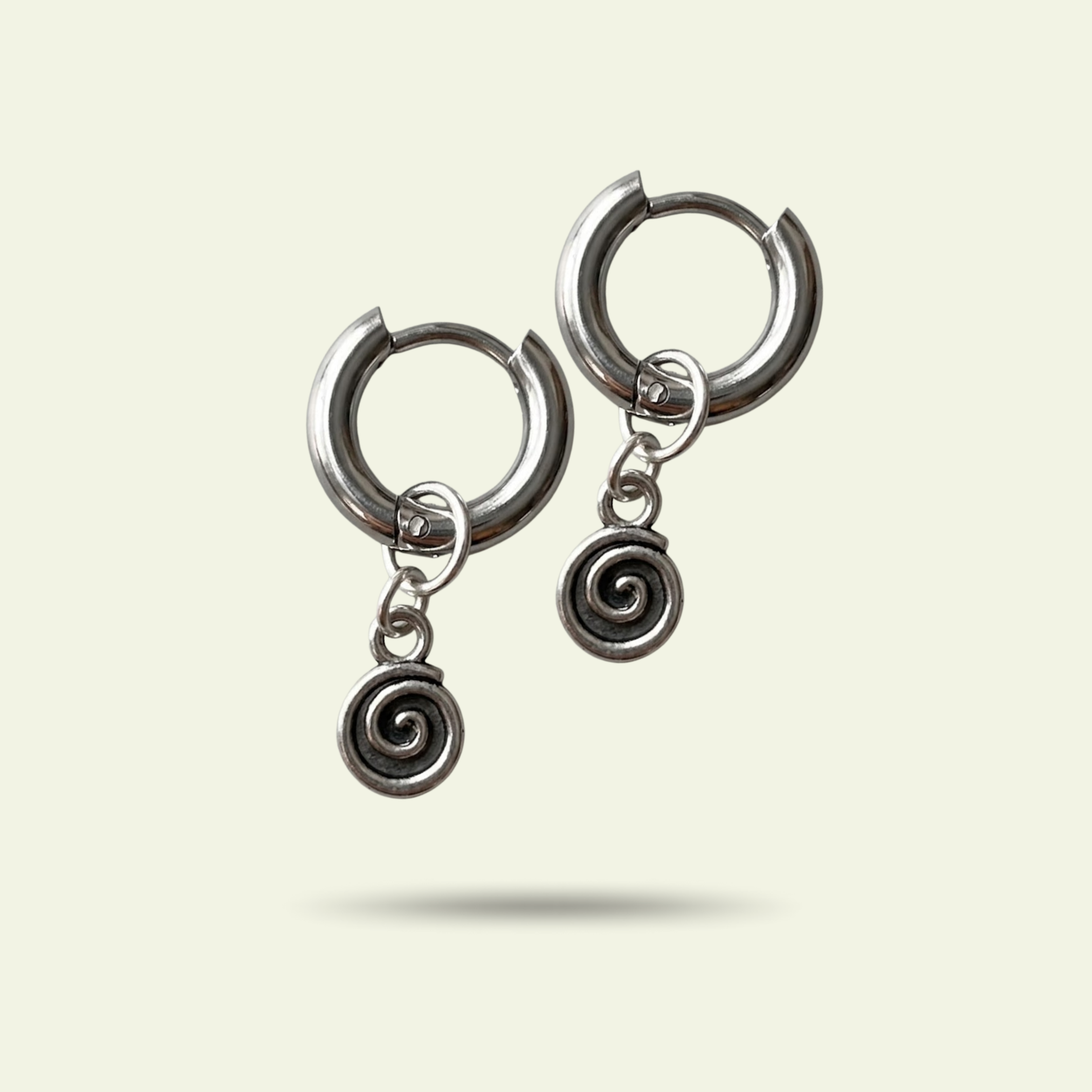 Pair of silver hoop earrings with spiral charms on a light beige background